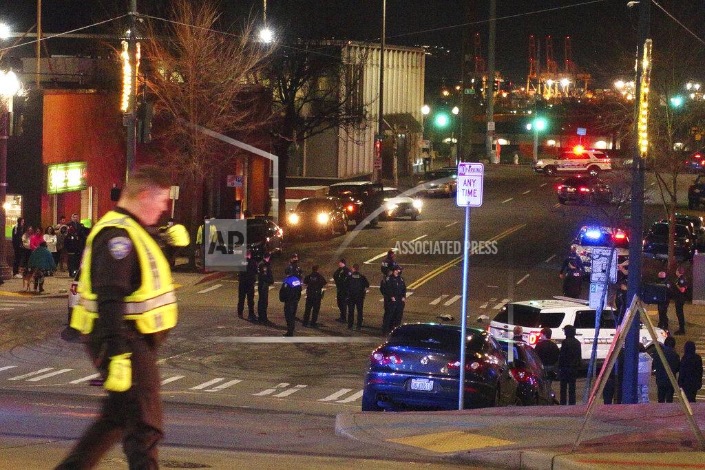 Ted S. Warren Tacoma Police and other law enforcement vehicles are shown near the site of a car crash Saturday, Jan. 23, 2021, in downtown Tacoma, Wash. At least one person was injured when a police car plowed through a crowd of people Saturday night who were watching a downtown street race, the Tacoma News-Tribune reported. (AP Photo/Ted S. Warren)