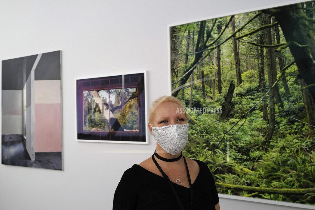 Francois Mori Heliante Bourdeaux-Maurin, H Gallery director, who is exhibiting at the fair, wears a protective face mask as a precaution against the coronavirus during the private view of Art Paris at the Grand Palais in Paris, Wednesday Sept. 9, 2020. Fears and restrictions over the coronavirus have caused the cancellation of all of 2020's premiere global art fairs, such as Art Basel, Frieze London, and Art Basel in Miami Beach, stymieing the main commercial artery of the multi-million-dollar industry.But organizers of Art Paris, France's second biggest contemporary art fair, have thrown caution to the wind, and are opening their doors to thousands of visitors from Thursday in the Grand Palais for a four-day show. (AP Photo/Francois Mori)