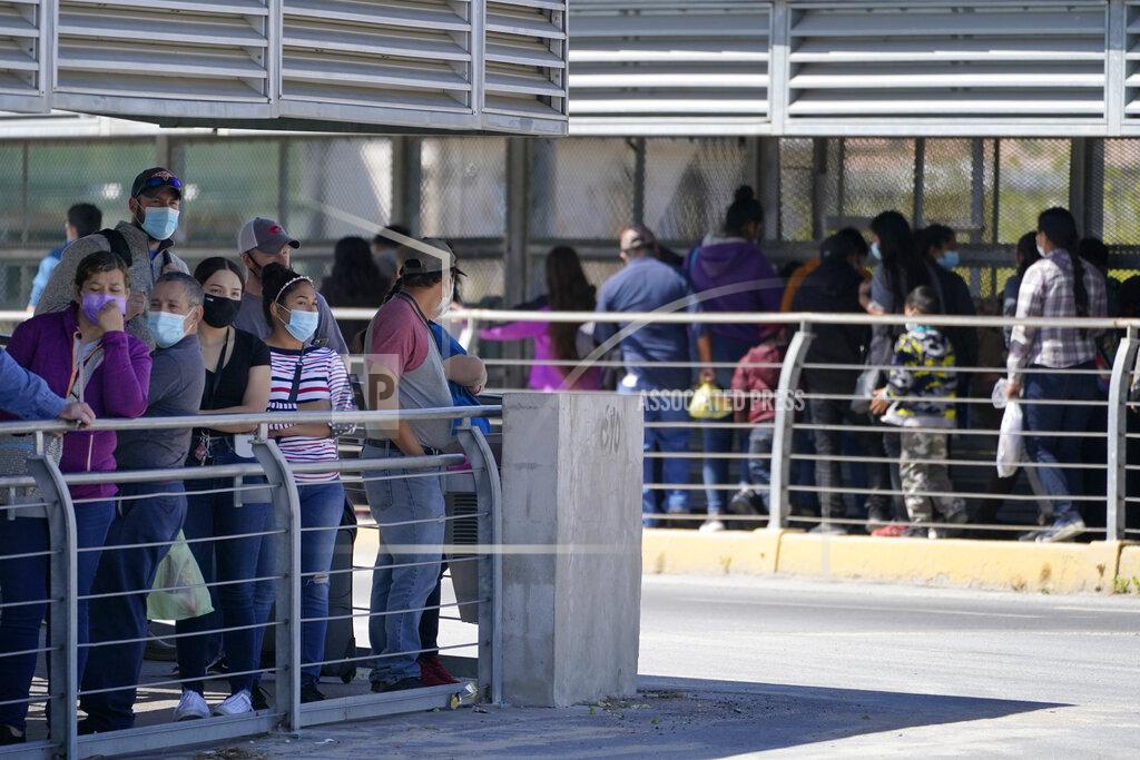 Julio Cortez Travelers, left, waiting in line to cross a customs area into the United States at the McAllen-Hidalgo International Bridge look on as a group of migrants, right, are deported to Reynosa, Mexico, Thursday, March 18, 2021, in Hidalgo, Texas. A surge of migrants on the Southwest border has the Biden administration on the defensive. The head of Homeland Security acknowledged the severity of the problem Tuesday but insisted it's under control and said he won't revive a Trump-era practice of immediately expelling teens and children. (AP Photo/Julio Cortez)