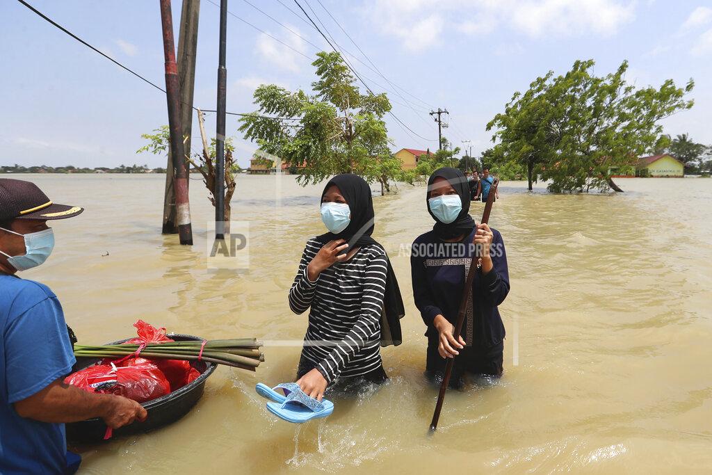 Achmad Ibrahim Indonesians carry their belongings as they wade through the water in a flooded neighborhood following heavy rains in Bekasi, Indonesia, Monday, Feb. 22, 2021. Thousands of residents are being evacuated on the outskirts of Indonesia’s capital amid flooding after the Citarum River embankment broke. (AP Photo/Achmad Ibrahim)