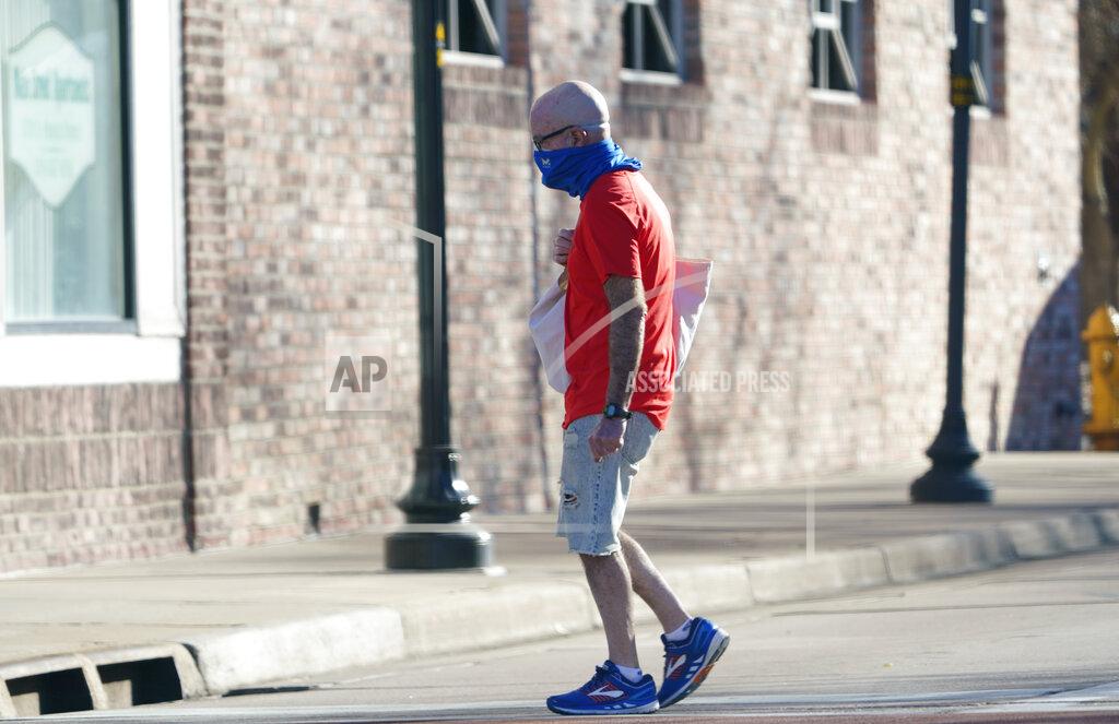 David Zalubowski FILE - In this Nov. 16, 2020, file photo, a lone pedestrian wears a face mask while moving along Main Street in Littleton, Colo. Colorado's Democrat-led Legislature is plowing ahead on special session legislation to provide limited state relief to businesses, students, and others affected by the coronavirus pandemic. The Senate on Tuesday, Dec. 1, 2020, unanimously passed bills to direct $5 million to help residents to pay utility bills; $50 million to assist landlords and tenants; and $100 million to the governor's office for use in the public health emergency. (AP Photo/David Zalubowski, File)