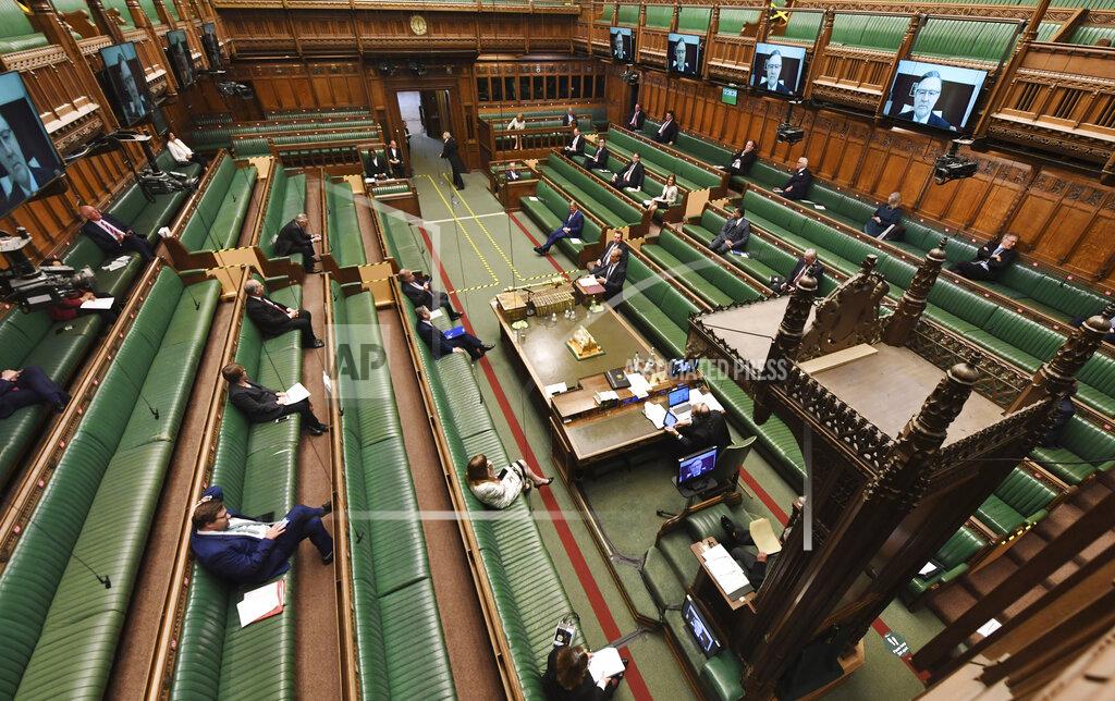 Jessica Taylor In this photo released by the UK Parliament, showing opposition Labour Party leader Keir Starmer, sitting centre left, faces Dominic Raab, standing centre right, inside of the House of Commons as members practice social distancing measures to combat COVID-19 coronavirus, as parliament goes online with most members of parliament participating via a video link, during Prime Minister's Questions time in London, Wednesday April 22, 2020. Dominic Raab answers a question, standing in for Prime Minister Boris Johnson who is still convalescing after contracting COVID-19 coronavirus. (Jessica Taylor/UK Parliament via AP)