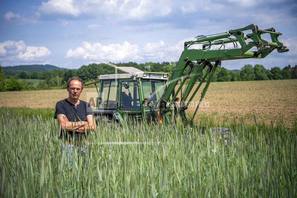 Lino Mirgeler Ulf Allhoff-Cramer, farmer, stands in a rye field in front of his tractor in Detmold, Germany, Wedenesday, May 18, 2022. The organic farmer holds the VW car company partly responsible for damage to his farm. Together with Greenpeace, he wants to go to court to get VW to stop producing combustion vehicles by 2030. (Lino Mirgeler/dpa via AP)
