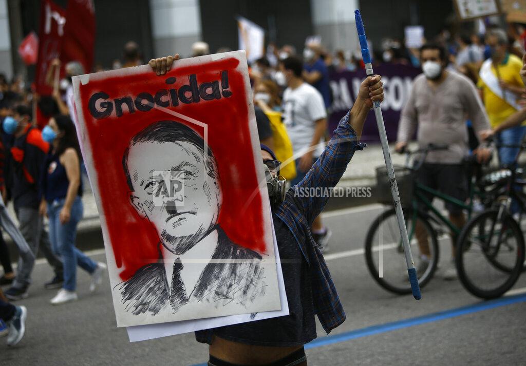 Bruna Prado A protester holds a poster depicting Brazilian President Jair Bolsonaro as Adolf Hitler and the Portuguese word for genocidal, during a demonstration against Bolsonaro's handling of the coronavirus pandemic and economic policies protesters say harm the interests of the poor and working class, in Rio de Janeiro, Brazil, Saturday, June 19, 2021. Brazil is approaching an official COVID-19 death toll of 500,000 — second-highest in the world. (AP Photo/Bruna Prado)