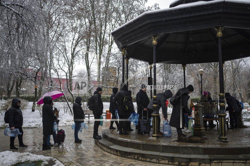 Evgeniy Maloletka People wait in line to collect water, in Kyiv, Ukraine, Thursday, Nov. 24, 2022. Residents of Ukraine's bombed but undaunted capital clutched empty bottles in search of water and crowded into cafés for power and warmth Thursday, switching defiantly into survival mode after new Russian missile strikes a day earlier plunged the city and much of the country into the dark. (AP Photo/Evgeniy Maloletka)