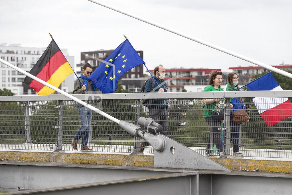 Jean-Francois Badias Members of pro-European French and German associations walk on a footbridge over the Rhine river and linking France to Germany, Sunday June 14, 2020 in Strasbourg, eastern France. The majority of European countries will be reopening Monday June 15, 2020 their borders and lifting the restrictions that had been in place during the COVID-19 pandemic. (AP Photo/Jean-Francois Badias)
