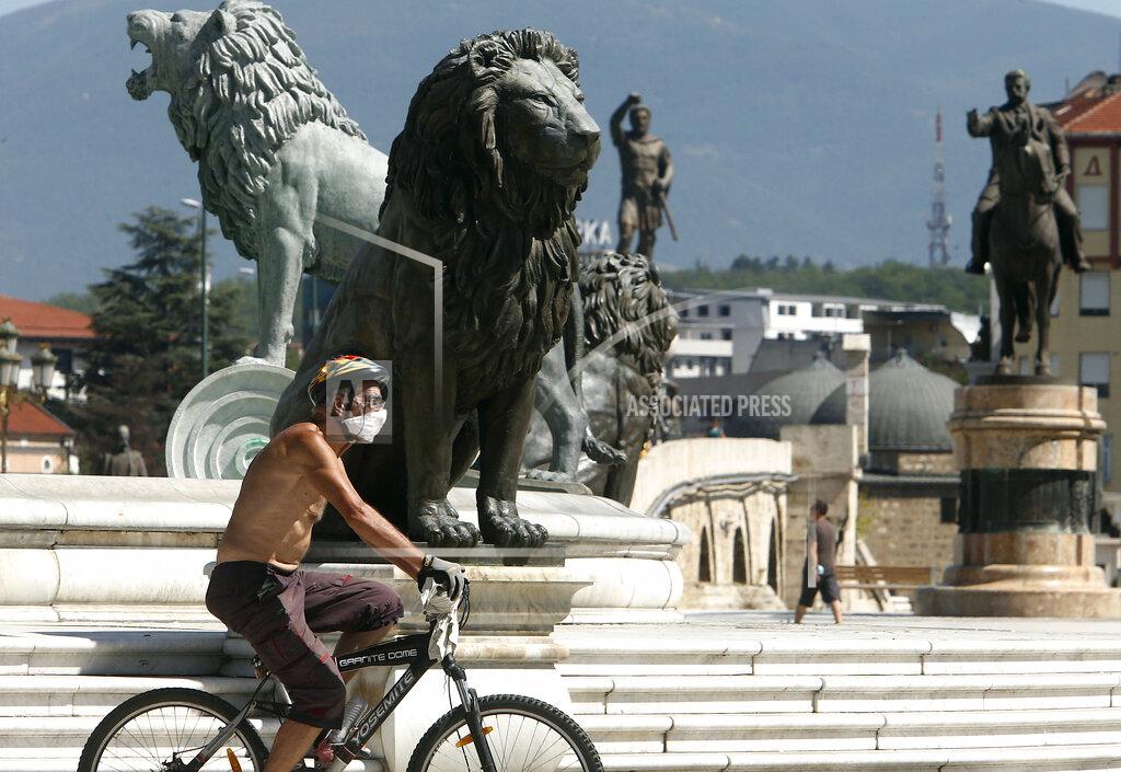Boris Grdanoski A man wearing a face mask rides a bicycle through the main square in Skopje, North Macedonia, Sunday, Aug. 30, 2020. North Macedonia's parliament continues Sunday the debate on a vote of confidence for a new left-wing coalition government after the Social Democrats and their ethnic Albanian partners secured a majority of seats in July's general election. (AP Photo/Boris Grdanoski)