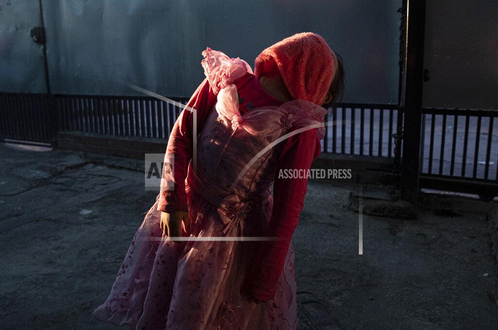 Esteban Felix Kehity Collantes shows off how she's going to use her pink scarf as a mask after she lost her real one, as she wears her princess costume while waiting outside her home to go to the park with her father in Santiago, Chile, Aug. 30, 2020, two months after losing her mother to the new coronavirus. For many pandemic survivors and those who lost loved ones, like five-year-old Collantes, the tragedy lingers and their lives are never the same. (AP Photo/Esteban Felix)