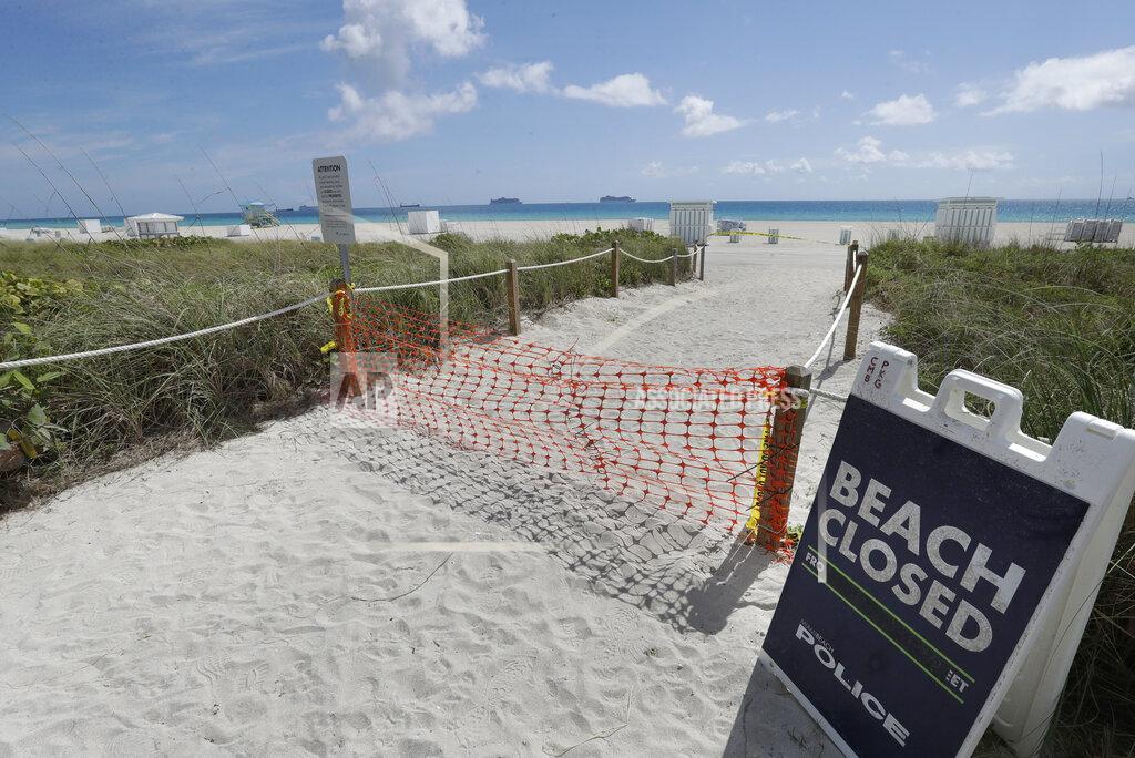 Wilfredo Lee FILE - In this Tuesday, March 31, 2020 file photo, an entrance to a beach is shown closed, in Miami Beach, Florida's famed South Beach. Memorial Day weekend historically signifies the start of the summer vacation season as families throughout the U.S. plan trips to Florida's beaches and theme parks. Miami-Dade County officials aren't expecting crowds, as the beaches remain closed. (AP Photo/Wilfredo Lee, File)