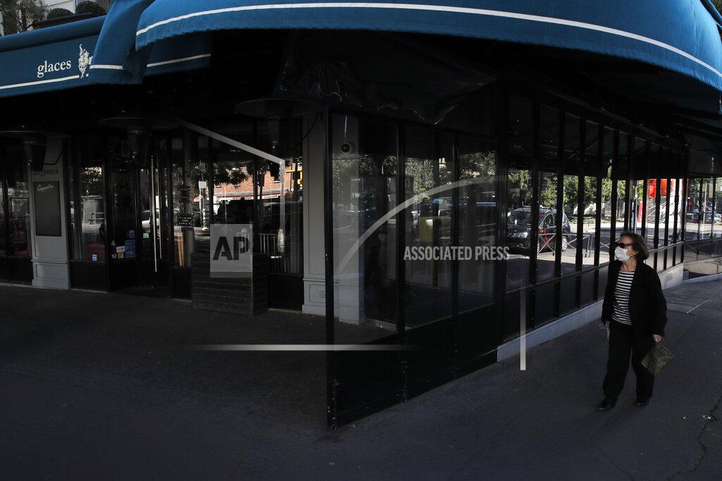 A woman walks past an empty terrace of a restaurant in Paris, Thursday, May 28, 2020. France is reopening its restaurants, bars and cafes starting next week as the country eases most restrictions amid the coronavirus crisis. Edouard Philippe defended the gradual lifting of lockdown up to now, saying the strategy was meant to avoid provoking a second wave. (AP Photo/Christophe Ena)