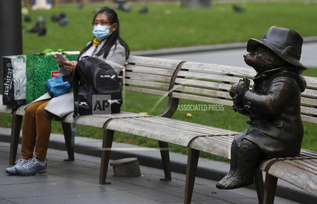 Frank Augstein A woman rests sits with shopping next to a statue of Paddington Bear in London, Friday, Oct. 9, 2020. The British economy grew by far less than anticipated during August, raising concerns that the recovery from the coronavirus recession was already stuttering even before the reimposition of an array of lockdown restrictions. (AP Photo/Frank Augstein)
