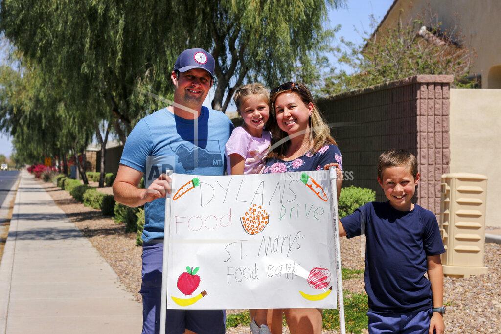 Cheyanne Mumphrey Nick, Evelyn, Erin and Dylan Pfeifer stand together near their home in Chandler, Ariz., holding a hand-drawn sign promoting a food drive on Saturday, April 3, 2021. Dylan Pfeifer hosted his third food drive since October in response to the coronavirus pandemic. “It’s been hard to interact with people, especially now, so this provides a safe way to do that. I just wanted to provide him a way to make an impact,” Erin Pfeifer said. (AP Photo/Cheyanne Mumphrey)