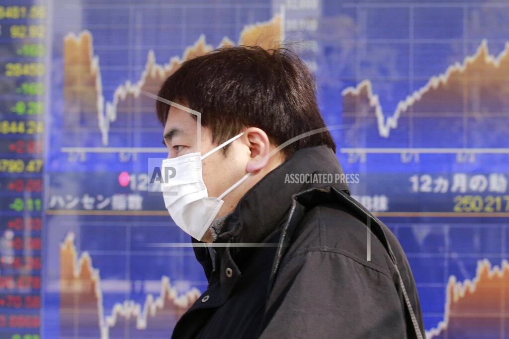 Koji Sasahara A man walks by an electronic stock board of a securities firm in Tokyo, Wednesday, Jan. 20, 2021. Asian shares were mostly higher Wednesday, ahead of Joe Biden's inauguration as president, ending President Donald Trump’s four-year term. Japan's benchmark lost early gains as worries grew about the surge in coronavirus cases. (AP Photo/Koji Sasahara)