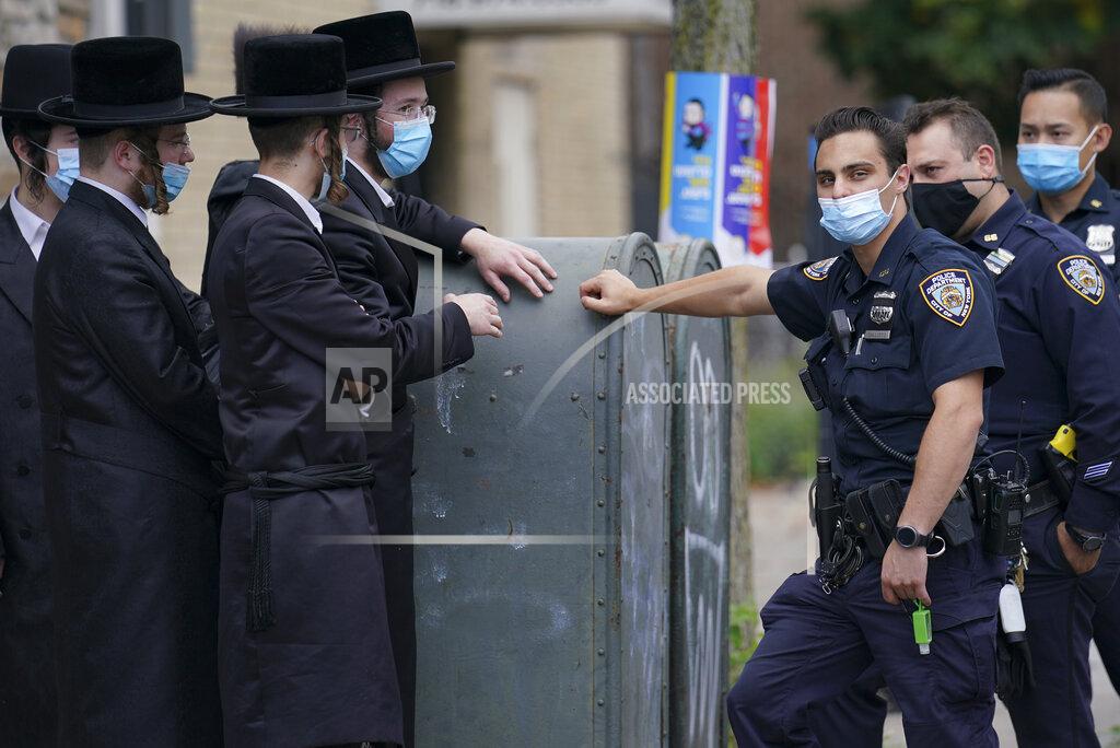 John Minchillo Members of the Orthodox Jewish community speak with NYPD officers, Wednesday, Oct. 7, 2020, in the Borough Park neighborhood of the Brooklyn borough of New York. Gov. Andrew Cuomo moved to reinstate restrictions on businesses, houses of worship and schools in and near areas where coronavirus cases are spiking. Many neighborhoods that stand to be affected are home to large enclaves of Orthodox Jews. (AP Photo/John Minchillo)