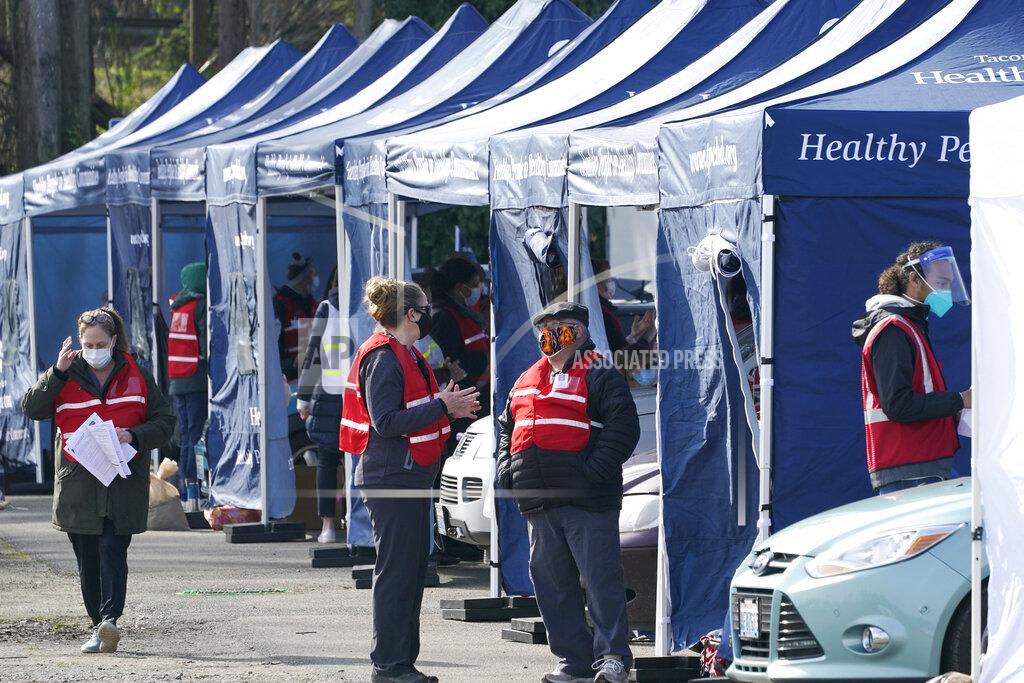 Ted S. Warren Workers stand near tents at a drive-up mass vaccination site, Thursday, March 4, 2021, in Puyallup, Wash., south of Seattle. Officials said they expected to deliver approximately 2500 second doses of the Moderna COVID-19 vaccine at the site Thursday. (AP Photo/Ted S. Warren)