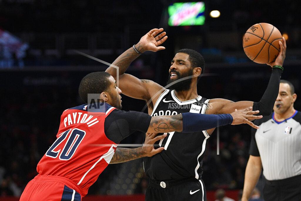FILE - Brooklyn Nets guard Kyrie Irving (11) looks to pass as he is defended by Washington Wizards guard Gary Payton II (20) during an NBA basketball game, in a Saturday, Feb. 1, 2020 file photo, in Washington. Brooklyn Nets star Kyrie Irving is committing $1.5 million to supplement the income of WNBA players who choose not to play this season. The funds will come from the KAI Empowerment Initiative that Irving launched Monday, July 27, 2020. (AP Photo/Nick Wass, file)