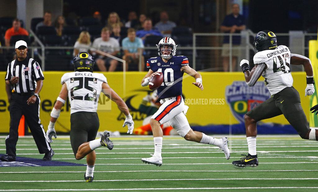 Ron Jenkins Auburn quarterback Bo Nix (10) looks to pass as Oregon safety Brady Breeze (25) and Oregon defensive end Gus Cumberlander (45) pursue during the first half of an NCAA college football game, Saturday, Aug. 31, 2019, in Arlington, Texas. (AP Photo/Ron Jenkins)