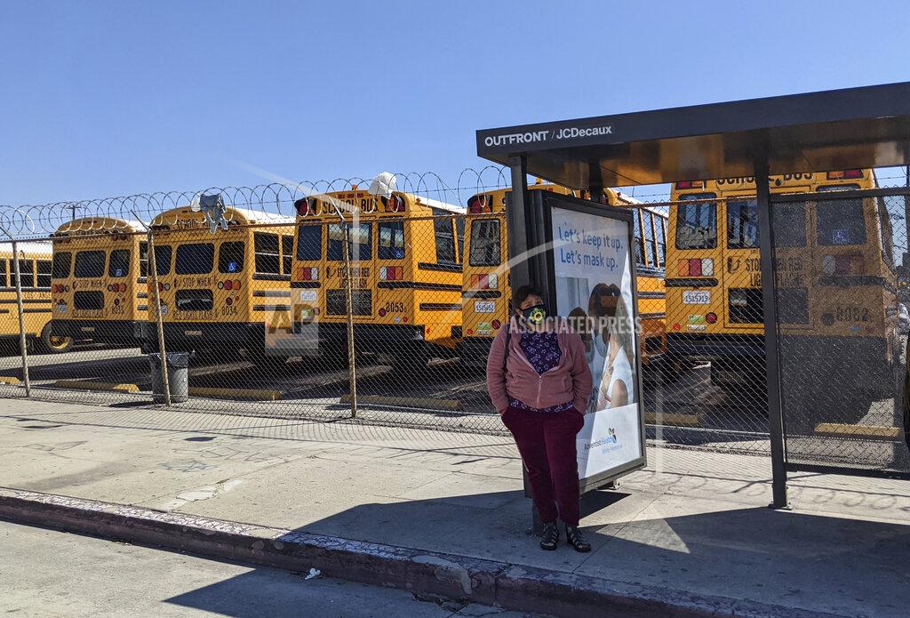 Damian Dovarganes In this Tuesday, March 16, 2021, photo, school buses remain parked in Los Angeles. Students in California classrooms can sit 3 feet apart instead of 6 under new guidelines adopted by the state as school officials figure out how to reopen campuses closed for a year during the coronavirus pandemic. (AP Photo/Damian Dovarganes)