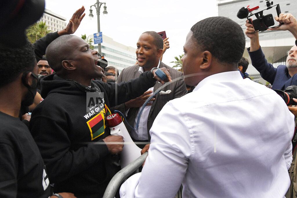 Mark J. Terrill Community organizer Robert Foster, center, and California 43rd Congressional candidate Joe Collins, right, speak to a crowd of protesters while Los Angeles Police Chief Michel Moore speaks about 100 feet away during a vigil with members of professional associations and the interfaith community at Los Angeles Police Department headquarters, Friday, June 5, 2020, in Los Angeles. The two men were also part of the vigil. (AP Photo/Mark J. Terrill)