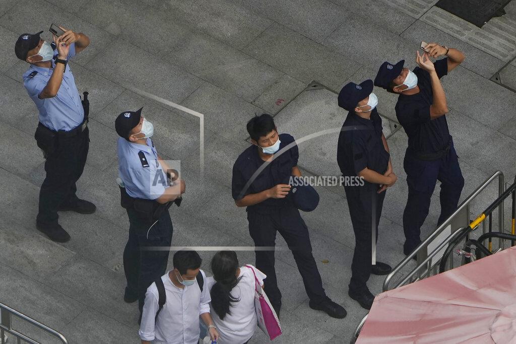 Ng Han Guan Police officers and security personnel react to something in the sky near the headquarters of the real estate developer Evergrande Group, Thursday, Sept. 23, 2021, in Shenzhen, southern China. Fears that the developer's possible default on multibillion-dollar debts might send shockwaves through global financial markets appeared to ease Thursday as creditors waited to see how much they might recover. (AP Photo/Ng Han Guan)