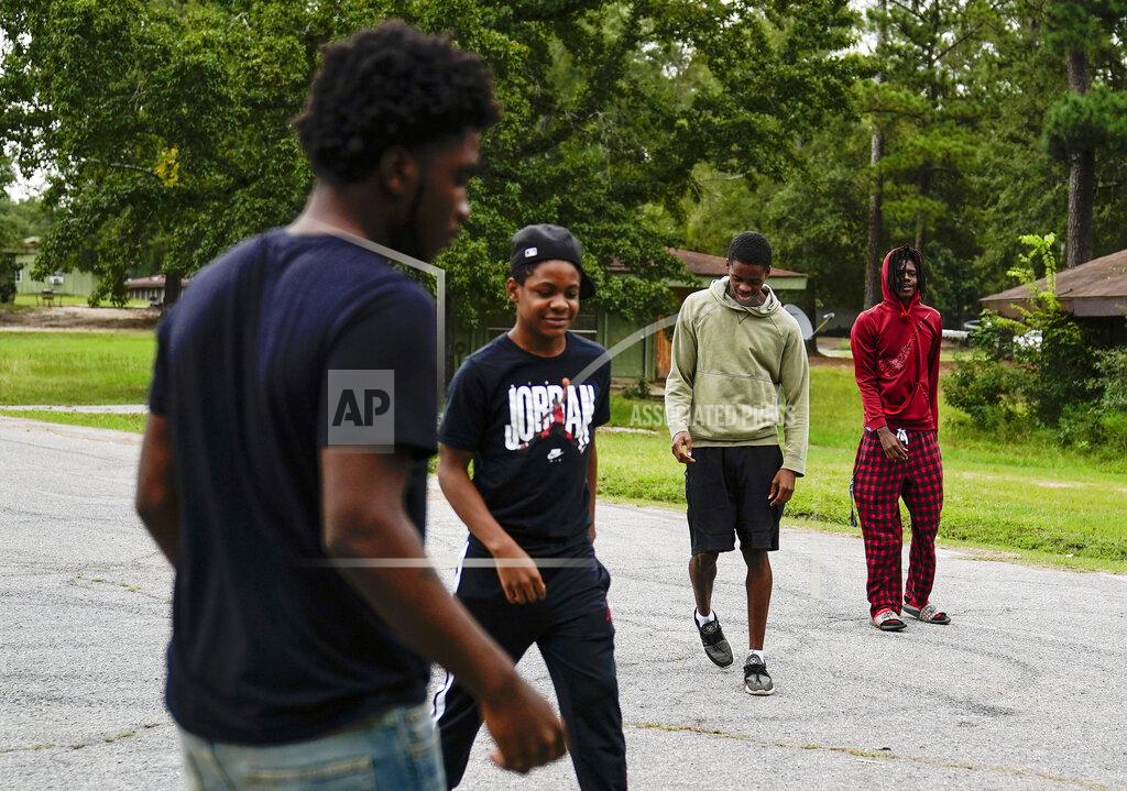 Brynn Anderson Voen Ivey, 18, left, JJ Ivey, 13, right center, Jay Johnson, 19, center, and Te Moss, 18, right, gather in front of their neighborhood in Hancock County, Saturday, Sept. 19, 2020, in Mayfield, Ga. Early on, victims of the coronavirus were mostly residents of the county's two nursing homes. Now, it's younger residents too. Coroner Adrick Ingram sees young people in town not wearing masks and gathering in big groups, and it frustrates him. ''I see people who aren't taking it seriously, maybe because they don't see what I see. They don't get to look in people's faces when they've lost somebody.'' (AP Photo/Brynn Anderson) (AP Photo/Brynn Anderson)