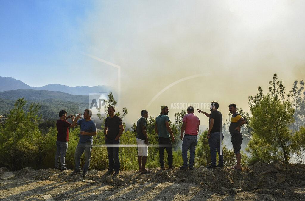 Uncredited People watch the wildfires that continue to rage the forests in Manavgat, Antalya, Turkey, early Sunday, Aug. 1, 2021. The fires in Antalya were continuing overnight in Manavgat and Gundogmus districts. In Bodrum, Mugla, they continued to burn down forests, encroaching on villages and tourist destinations and forcing people to evacuate by boats. (AP Photo)