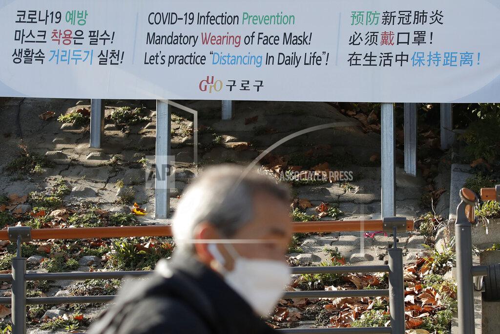 Lee Jin-Man A man wearing a face mask walks past a banner showing precautions against the coronavirus in Seoul, South Korea, Monday, Nov. 23, 2020. (AP Photo/Lee Jin-man)