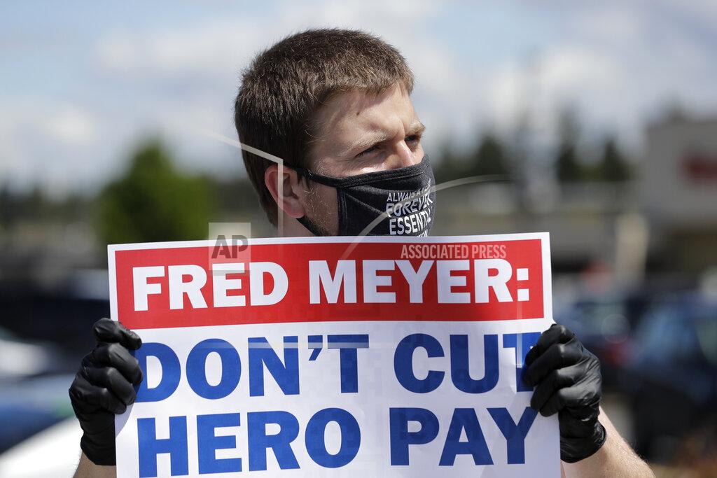 Ted S. Warren Sherman Jenne, a cashier at the Fred Meyer grocery store in Burien, Wash., takes part in a protest outside the store against Fred Meyer's parent company Kroger, Friday, May 15, 2020, that was organized by the United Food and Commercial Workers International Union. Kroger officials have said they are ending the additional $2 hourly "hero pay" bonus that had been paid to workers since late March during the coronavirus pandemic. The company said Friday it will now offer one-time bonus payments of $400 and $200 for full- and part-time employees to be paid in two installments. (AP Photo/Ted S. Warren)