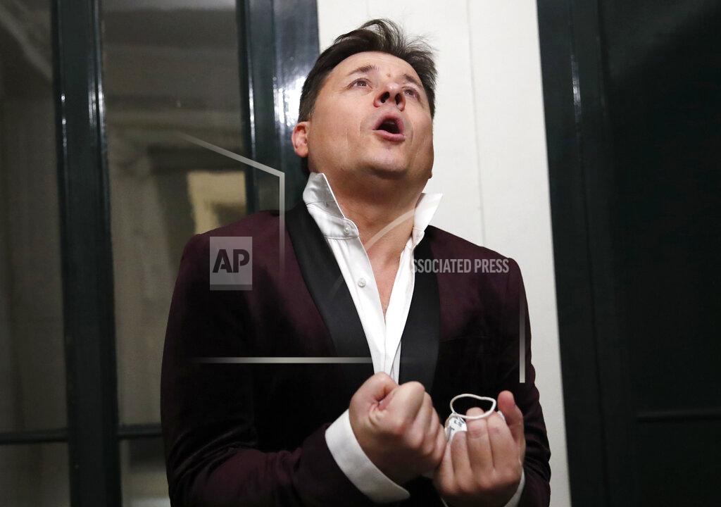 Francois Mori FILE - French tenor singer Stephane Senechal performs after he sings at dusk, the U.S. national anthem and Tosca of Puccini, from his apartment window during the monthlong partial lockdown to stop fast-rising virus hospitalizations and deaths, in Paris, Nov. 09, 2020. Senechal, along with professional and amateur musicians, sang from their balconies or windows to uplift neighbors. (AP Photo/Francois Mori, File)