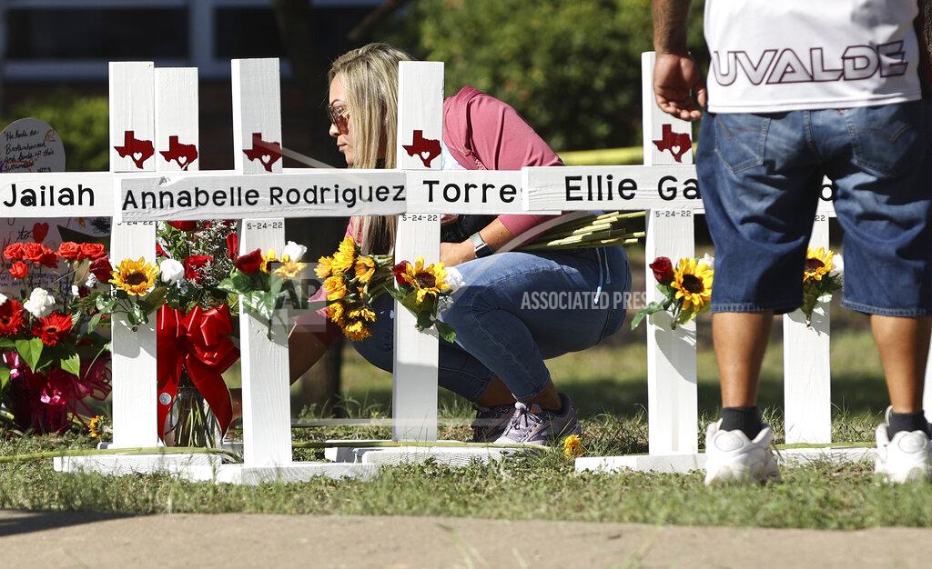 Kin Man Hui A mourner places flowers by each of the wooden crosses at a memorial site for the victims of the Robb Elementary School shooting, Thursday, May 26, 2022, in Uvalde, Texas. (Kin Man Hui/The San Antonio Express-News via AP)