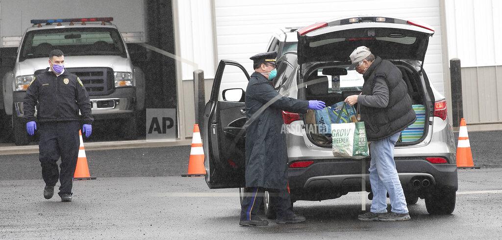 This May 1, 2020 photo, Sgt. David Blythe accepts a donation from Steve Hall, of Wallingford, Conn., during a food drive to benefit local pantries at the Wallingford Police Dept. (Dave Zajac/Record-Journal via AP)