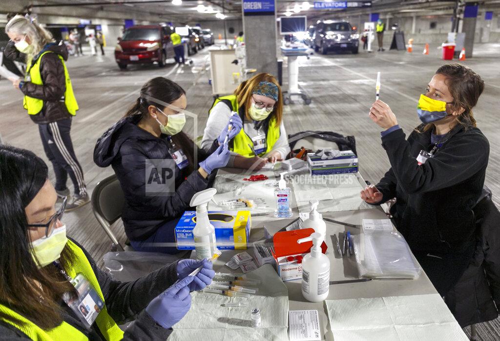 FILE - In this Jan. 10, 2021, file photo, medical professionals from Oregon Health & Science University load syringes with the Moderna COVID-19 vaccine at a drive-thru vaccination clinic in Portland, Ore. Oregon health officials and vaccine advisory committee have made critical, and often controversial, decisions about which groups of people should be prioritized next for the COVID-19 vaccine amid limited supply. Under a new pilot program this week, at least seven federally qualified health centers in Oregon are now able to inoculate whoever they want, even if that patient does not fall into currently eligible categories. (Kristyna Wentz-Graff/Pool Photo via AP, File)