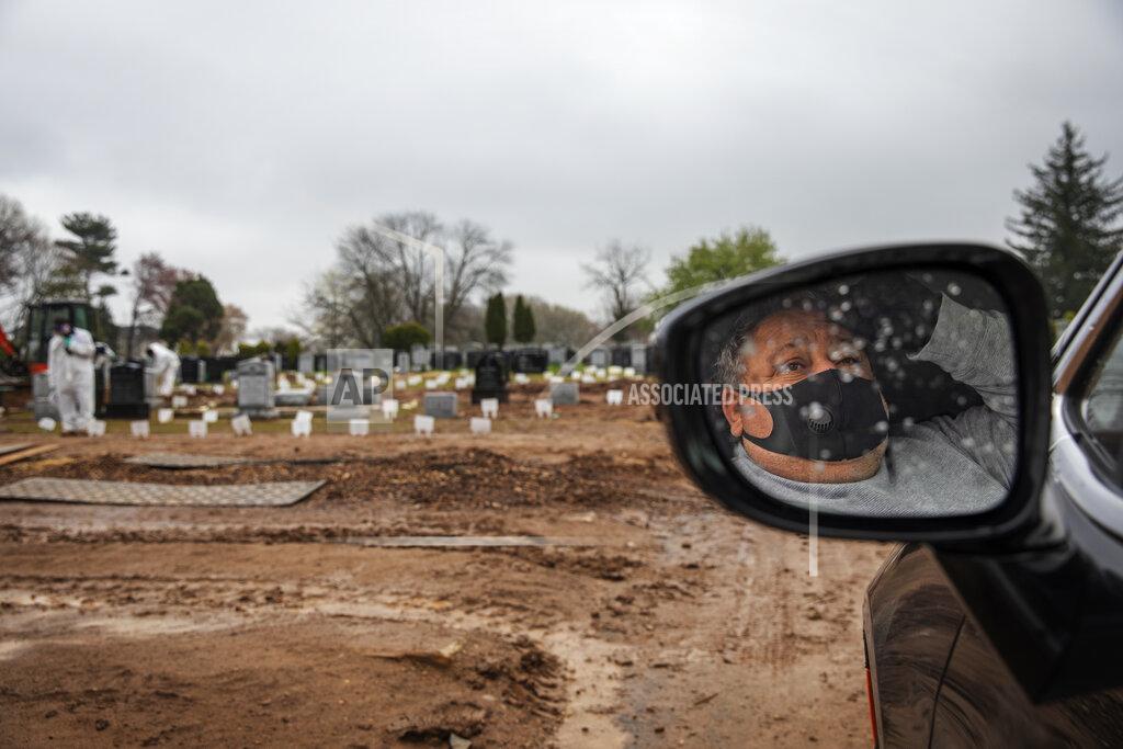 David Goldman Michael Tokar observes from his car as his father, David Tokar, is buried at Mount Richmond Cemetery in the Staten Island borough of New York, Wednesday, April 8, 2020. Tokar's father had a cough and fever and a home health aide got him to the hospital. Two days later, he was dead, with the coronavirus listed as the cause. (AP Photo/David Goldman)