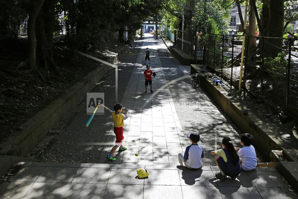 Kiichiro Sato FILE - In this April 19, 2020, file photo, children, some wearing protective masks to prevent the spread of the coronavirus, play baseball on a walkway to Shibuya Hikawa-Jijja shinto shrine in Tokyo. Under Japan's coronavirus state of emergency, people have been asked to stay home. Many are not. Some still have to commute to their jobs despite risks of infection, while others are dining out, picnicking in parks and crowding into grocery stores with scant regard for social distancing. (AP Photo/Kiichiro Sato, File)