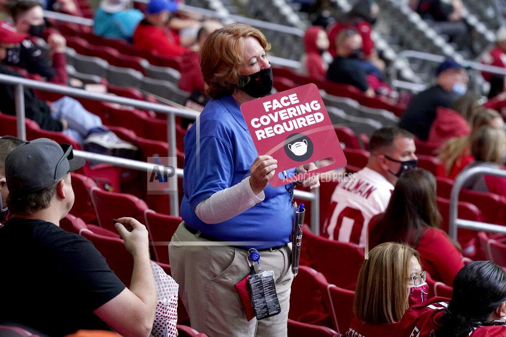Ross D. Franklin An Arizona Cardinals guest relations attendant highlights face mask requirements to fans during the second half of an NFL football game against the Miami Dolphins, Sunday, Nov. 8, 2020, in Glendale, Ariz. (AP Photo/Ross D. Franklin)