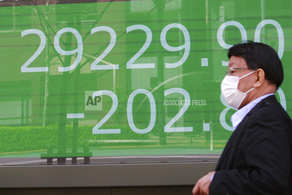 Koji Sasahara A man wearing a face mask walks by an electronic stock board of a securities firm in Tokyo, Wednesday, March 31, 2021. Asian shares were mixed Wednesday as data showed a strong economic recovery in China but worries lingered about the coronavirus pandemic. (AP Photo/Koji Sasahara)