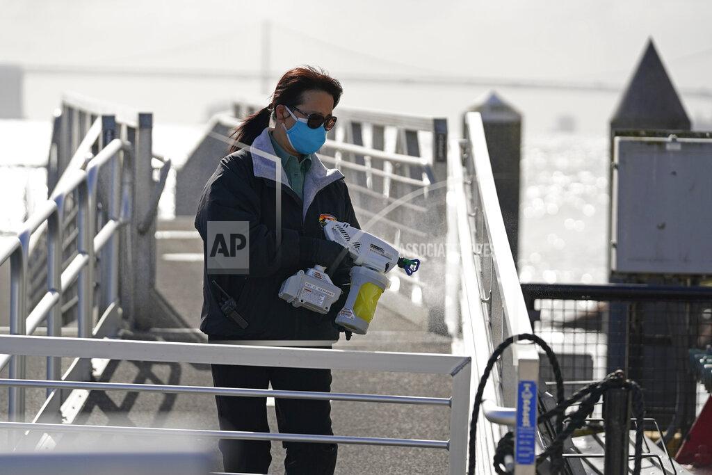 Eric Risberg A woman disinfects the handrails of the main dock gangway on Alcatraz Island in San Francisco, Monday, March 15, 2021. The historic island prison was reopened to visitors Monday after being closed since December because of the coronavirus threat. Visitors were also able to tour the inside of the main cell house for the first time in a year. (AP Photo/Eric Risberg)