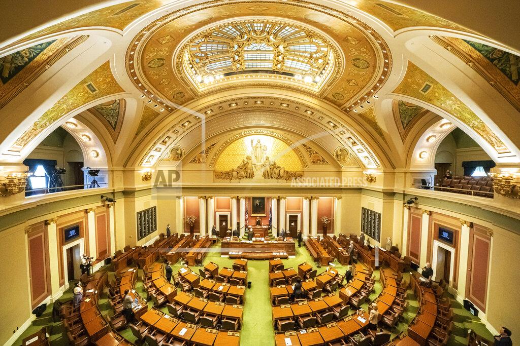 With most legislators working remotely, members present on the House floor stand for the Pledge of Allegiance in St. Paul, Minn., on Monday, Sept. 12, 2020, for the start of the fifth special session of the year, to review Gov. Tim Walz's emergency coronavirus powers. (Glen Stubbe/Star Tribune via AP)
