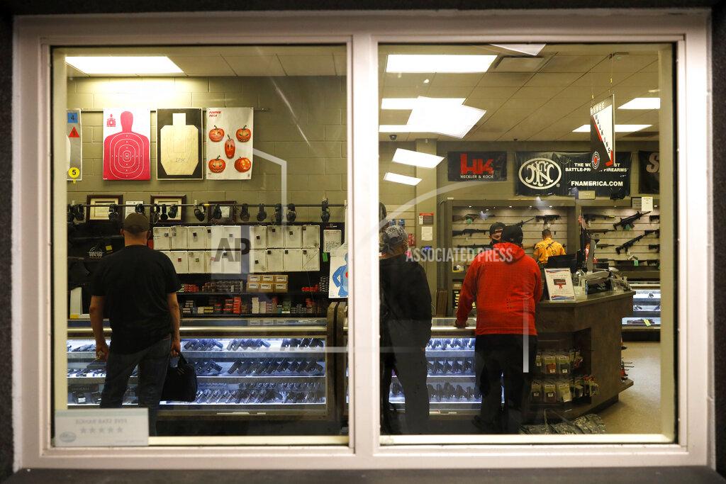 Shafkat Anowar Customers stand inside the gun shop area of Maxon Shooter's Supplies and Indoor Range, as seen from the shooting range, Friday, April 30, 2021, in Des Plaines, Ill. After a year of pandemic lockdowns, mass shootings are back, but the guns never went away. As the U.S. inches toward a post-pandemic future, guns are arguably more present in the American psyche and more deeply embedded in American discourse than ever before. The past year's anxiety and loss fueled a rise in gun ownership across political and socio-economic lines. (AP Photo/Shafkat Anowar)