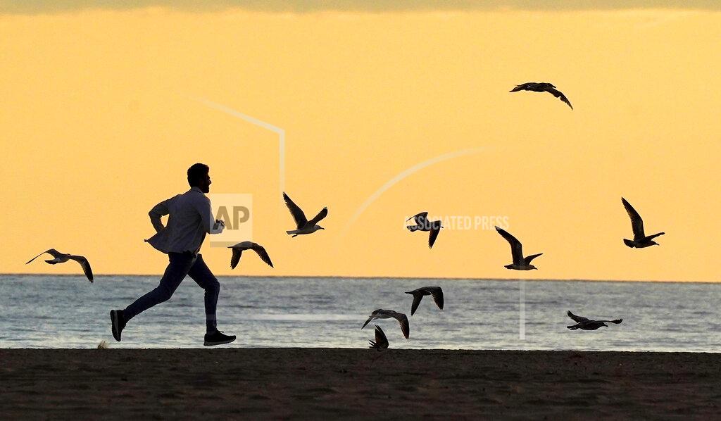 Mark J. Terrill A man chases seagulls on Santa Monica State Beach, Friday, April 10, 2020, in Santa Monica, Calif., during the coronavirus outbreak. (AP Photo/Mark J. Terrill)