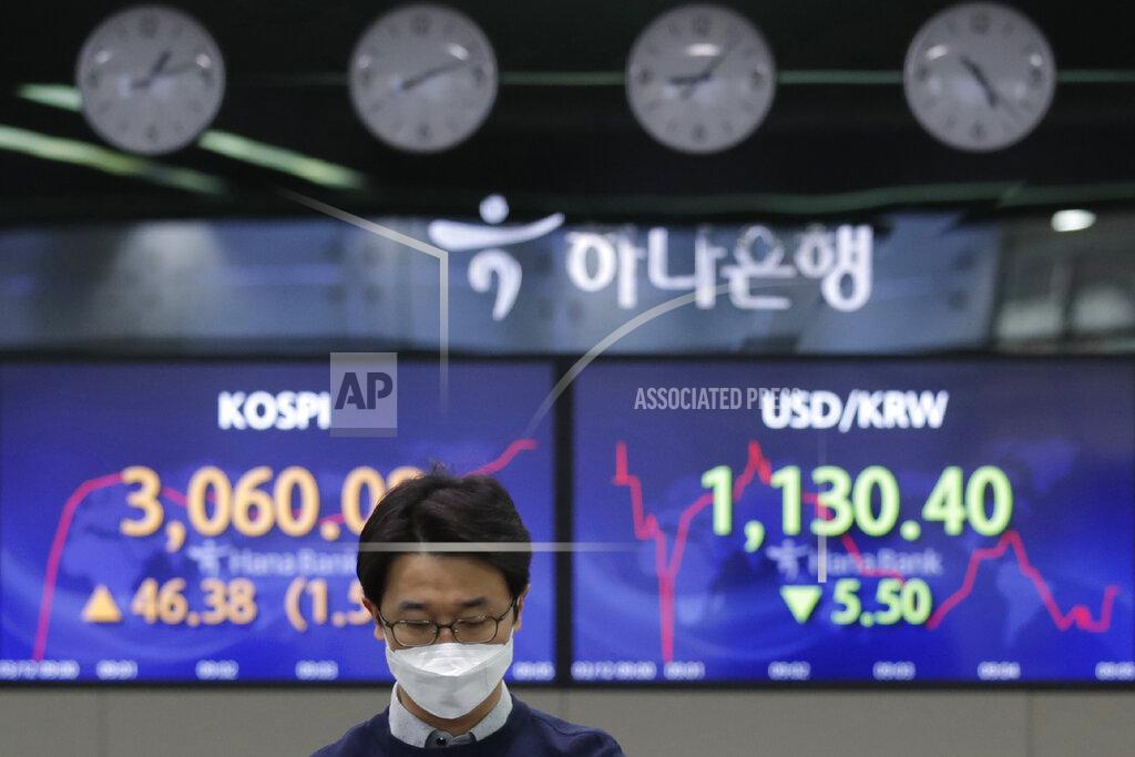 Lee Jin-Man A currency trader walks by the screens showing the Korea Composite Stock Price Index (KOSPI), left, and the foreign exchange rate between U.S. dollar and South Korean won at the foreign exchange dealing room in Seoul, South Korea, Friday, March 12, 2021. Stocks were mixed in Asia on Friday after broad gains lifted several major indexes to all-time highs on Wall Street. (AP Photo/Lee Jin-man)