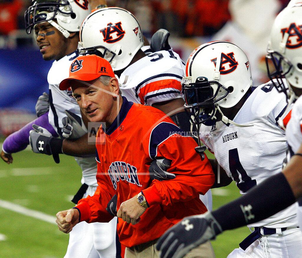 Ric Feld FILE - In this Dec. 4, 2004, file photo, Auburn coach Tommy Tuberville links arms with his players as the run onto the field prior to the Southeastern Conference football championship game against Tennessee, at the Georgia Dome in Atlanta. Players from left: Mayo Sowell (57), Travis Williams (51) and Junior Rosegreen. In 2004, more controversy ensued when USC, Oklahoma, Auburn, Utah and Boise State all went through the regular season undefeated. The BCS national title matchup, which in those days was partially decided by the AP poll, went to USC and Oklahoma while the other three were left out. (AP Photo/Ric Feld, File)