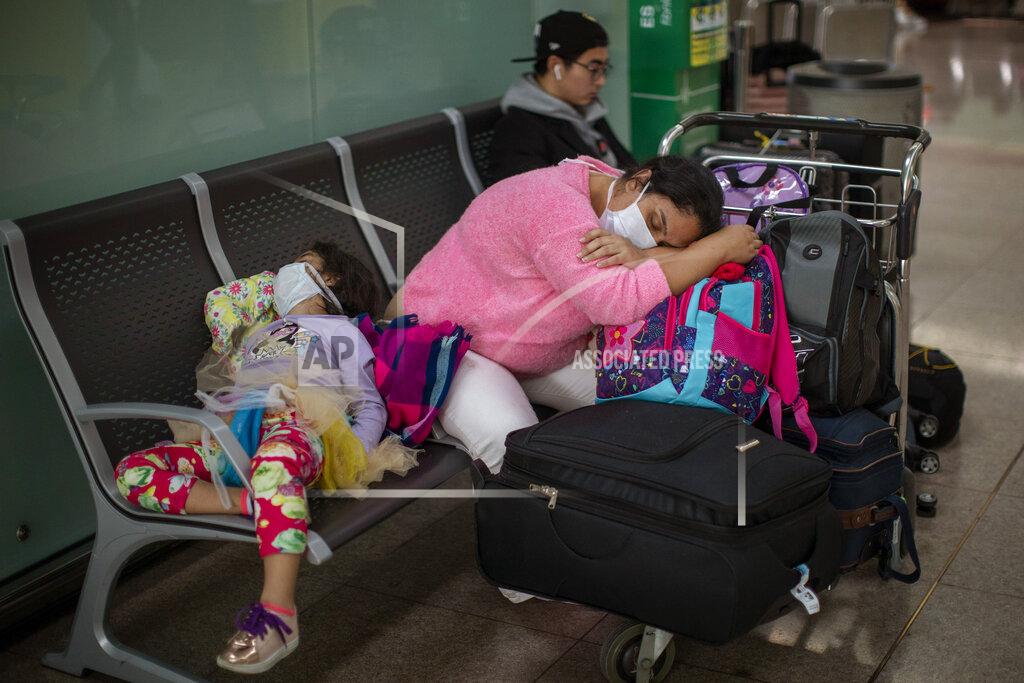 Emilio Morenatti FILE - In this March 12, 2020, file photo, passengers rest at the Barcelona airport, Spain. President Donald Trump, who had downplayed the coronavirus for weeks, suddenly struck a different tone, announcing strict rules on restricting travel from much of Europe to begin this weekend. (AP Photo/Emilio Morenatti, File)