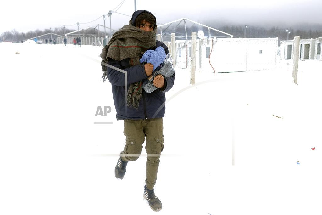 Kemal Softic A migrant carries footwear and blankets received from humanitarian organization at the Lipa camp, outside Bihac, Bosnia, Monday, Jan. 11, 2021. Aid workers say migrants staying at a camp in northwestern Bosnia have complained or respiratory and skin diseases after spending days in make-shift tents and containers amid freezing weather and snow blizzards. Most of the hundreds of migrants at the Lipa facility near Bosnia's border with Croatia on Monday have been accommodated in heated military tents following days of uncertainty after a fire gutted most of the camp on Dec. 23. (AP Photo/Kemal Softic)
