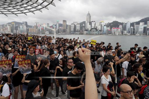 FILE - In this file photo, protesters march near the skyline of Hong Kong, on July 7, 2019. The exodus of tens of thousands of professionals from Hong Kong triggered by Beijing's crackdown on its civil liberties is being offset by new arrivals: mainland Chinese keen to move to the former British colony. (AP Photo/Kin Cheung, File)