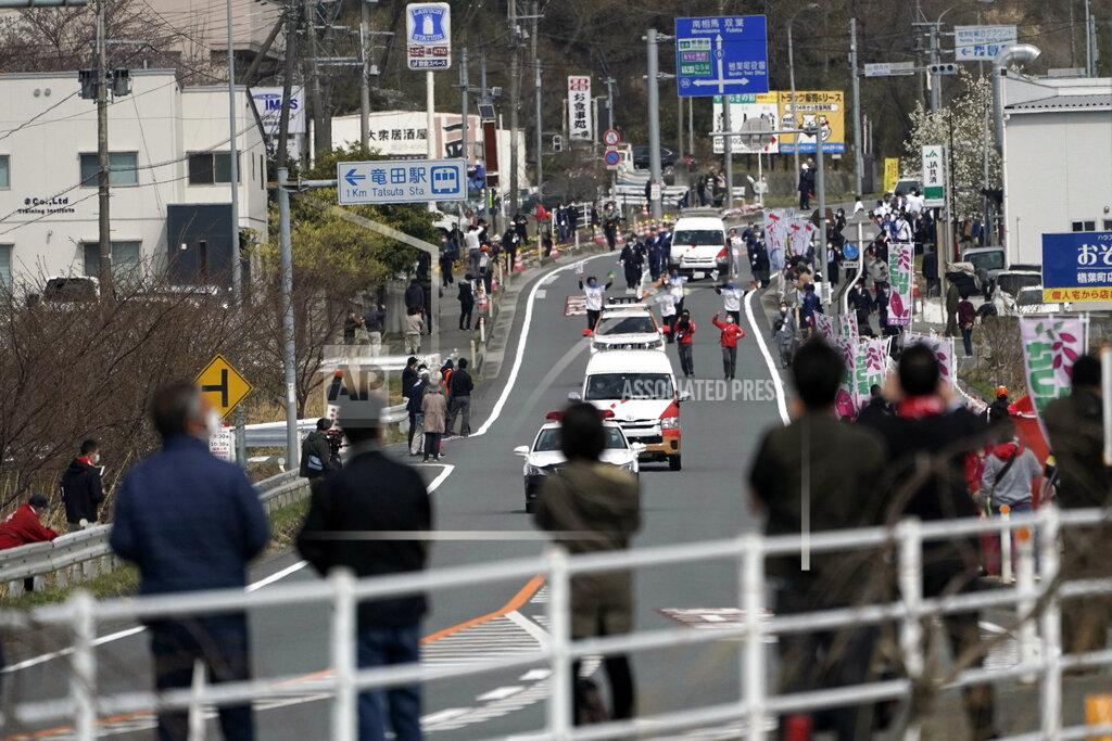 Eugene Hoshiko Local people cheer torchbearers and participants running at the torch relay route of the first section of the Fukushima Torch Relay in Naraha, Fukushima prefecture, northeastern Japan, Thursday, March 25, 2021. The torch relay for the postponed Tokyo Olympics began its 121-day journey across Japan on Thursday and is headed toward the opening ceremony in Tokyo on July 23. (AP Photo/Eugene Hoshiko)