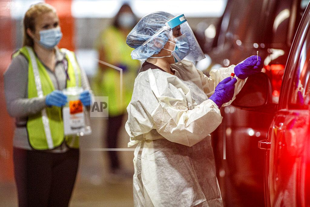 Medical staff work at a COVID-19 testing site at the Connecticut Convention Center in Hartford, Conn., on Wednesday, Nov. 11, 2020. An increase in demand for coronavirus testing in advance of Thanksgiving has led to hours-long lines across Connecticut as providers scramble to add capacity and hire new workers. (Mark Mirko/Hartford Courant via AP)