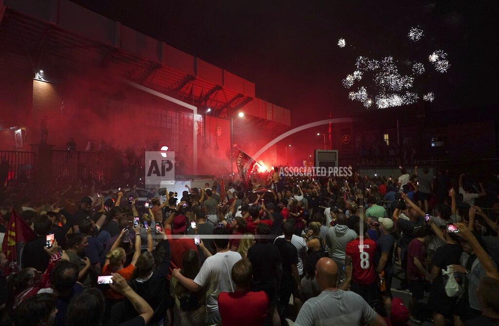 Jon Super Liverpool supporters celebrate as they gather outside of Anfield Stadium in Liverpool, England, Thursday, June 25, 2020 after Liverpool clinched the English Premier League title. Liverpool took the title after Manchester City failed to beat Chelsea on Wednesday evening. (AP photo/Jon Super)