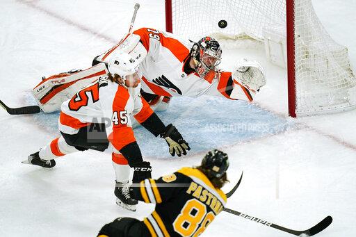 Boston Bruins right wing David Pastrnak (88) shoots past Philadelphia Flyers goaltender Carter Hart (79) for his second goal during the first period of an NHL hockey game, Thursday, Jan. 13, 2022, in Boston. Flyers defenseman Cam York (45) looks on. (AP Photo/Charles Krupa)