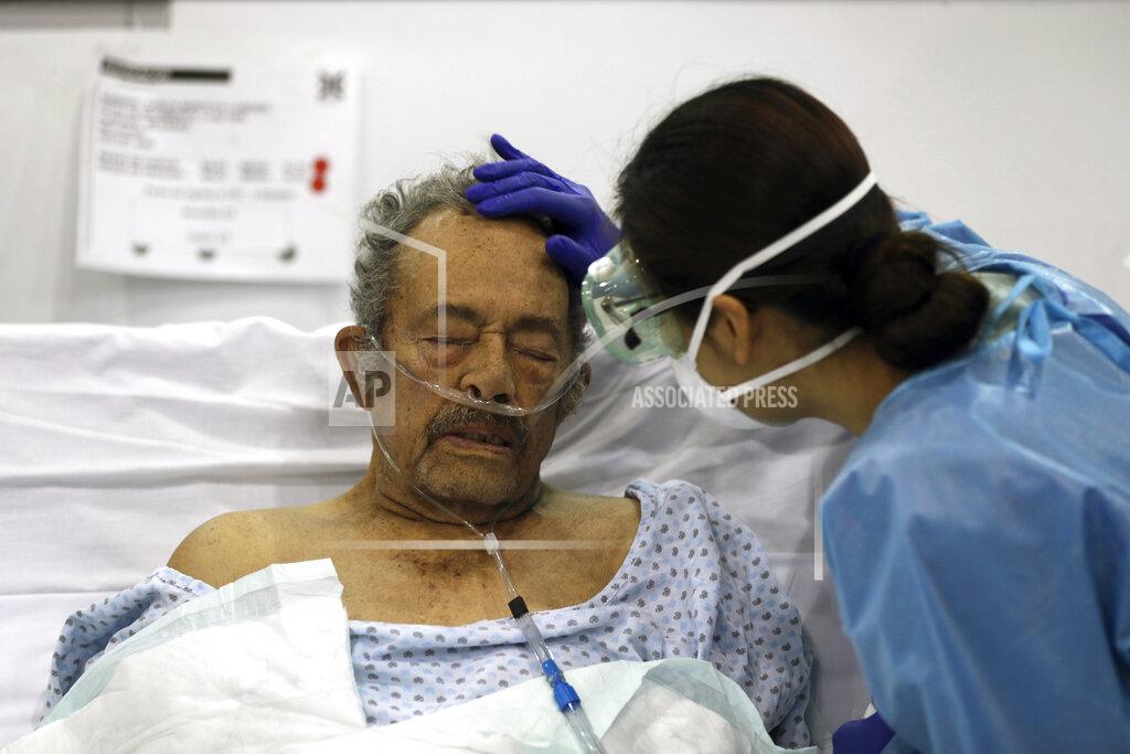 Fernando Llano FILE - In this March 11, 2021 file photo, a healthcare worker strokes the forehead of a COVID-19 patient at a field hospital built inside the Citibanamex convention center in Mexico City. According to a report released the third week of April, by the University of California, San Francisco, Mexico would have had a significantly lower COVID-19 death toll if it had reacted as well as the average government. (AP Photo/Fernando Llano, File)